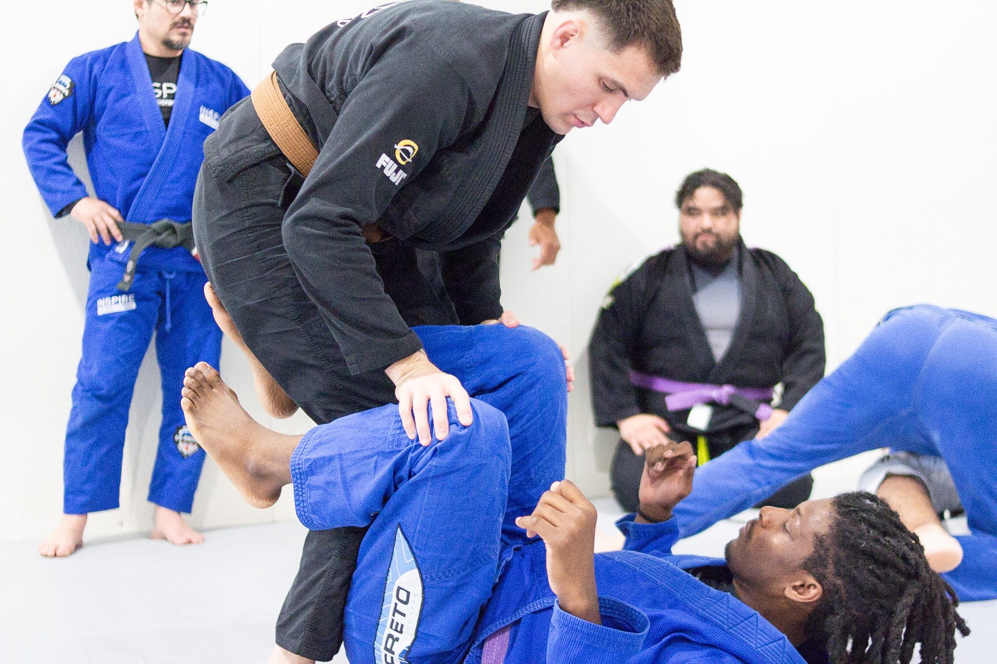 Brown belt coach teaching a standing guard break to students in a Pearland BJJ class