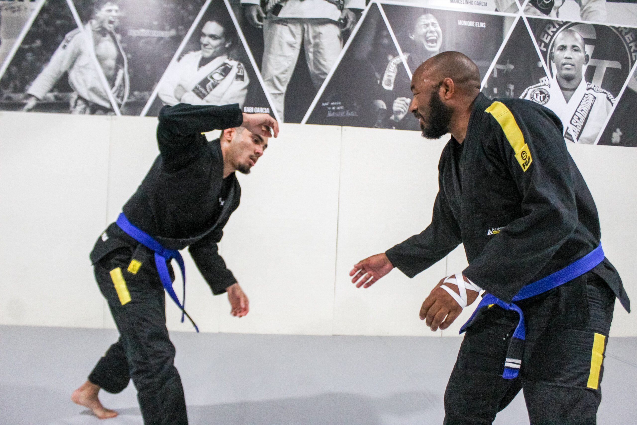 Two adult BJJ students in blue belts squaring up for a stand-up grip fight