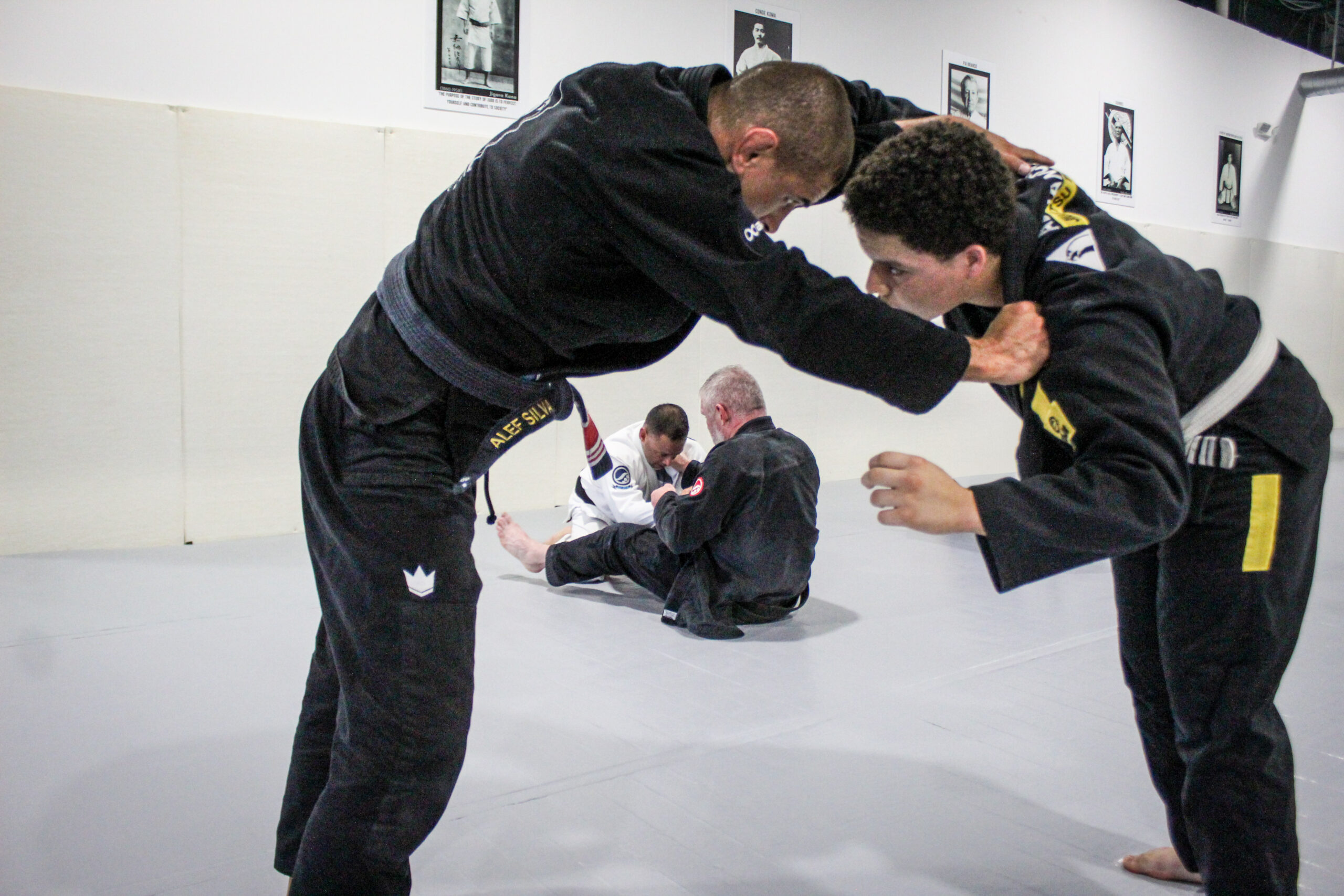 Two adult students drilling stand-up technique while coach Alef oversees the class
