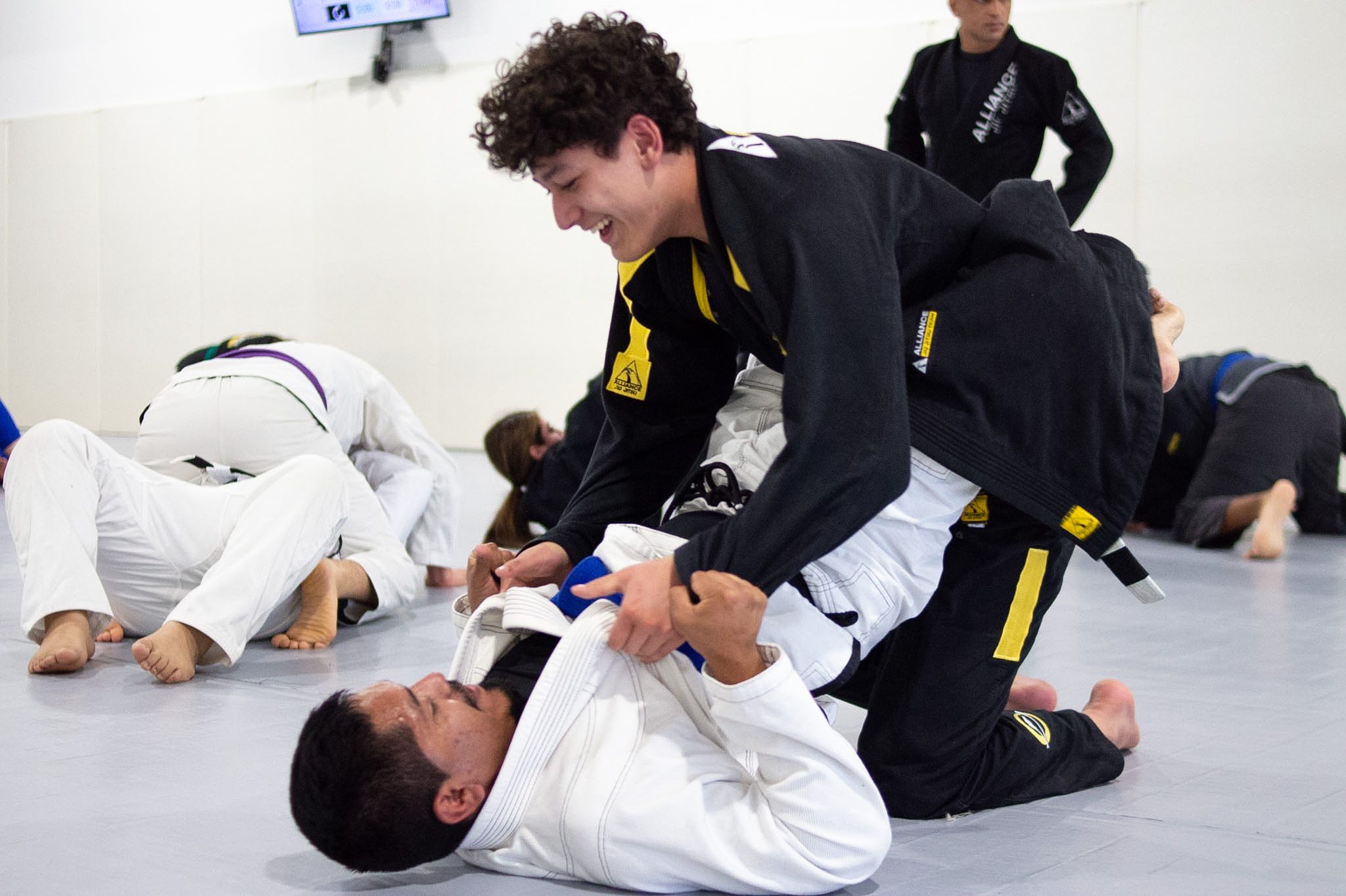 Young grappler passing guard while training partner smiles