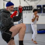 Adult Muay Thai student drilling knee strikes with hand wraps during shadow work