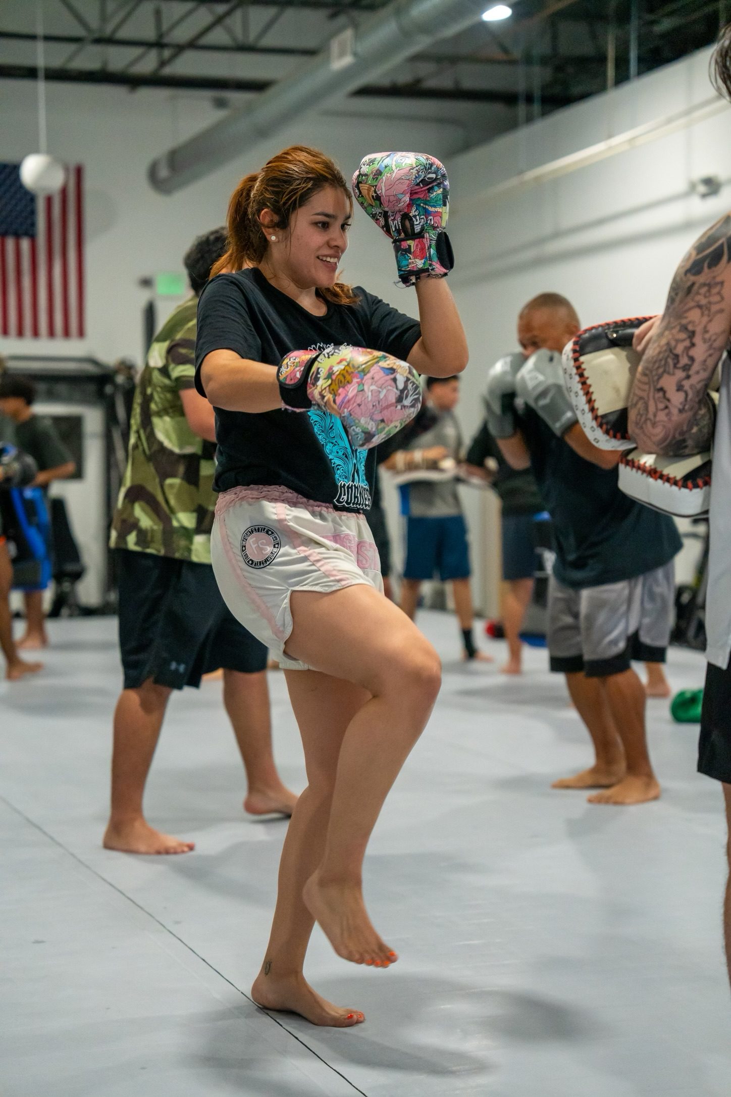 Female Muay Thai student throwing a knee on the heavy bag during class