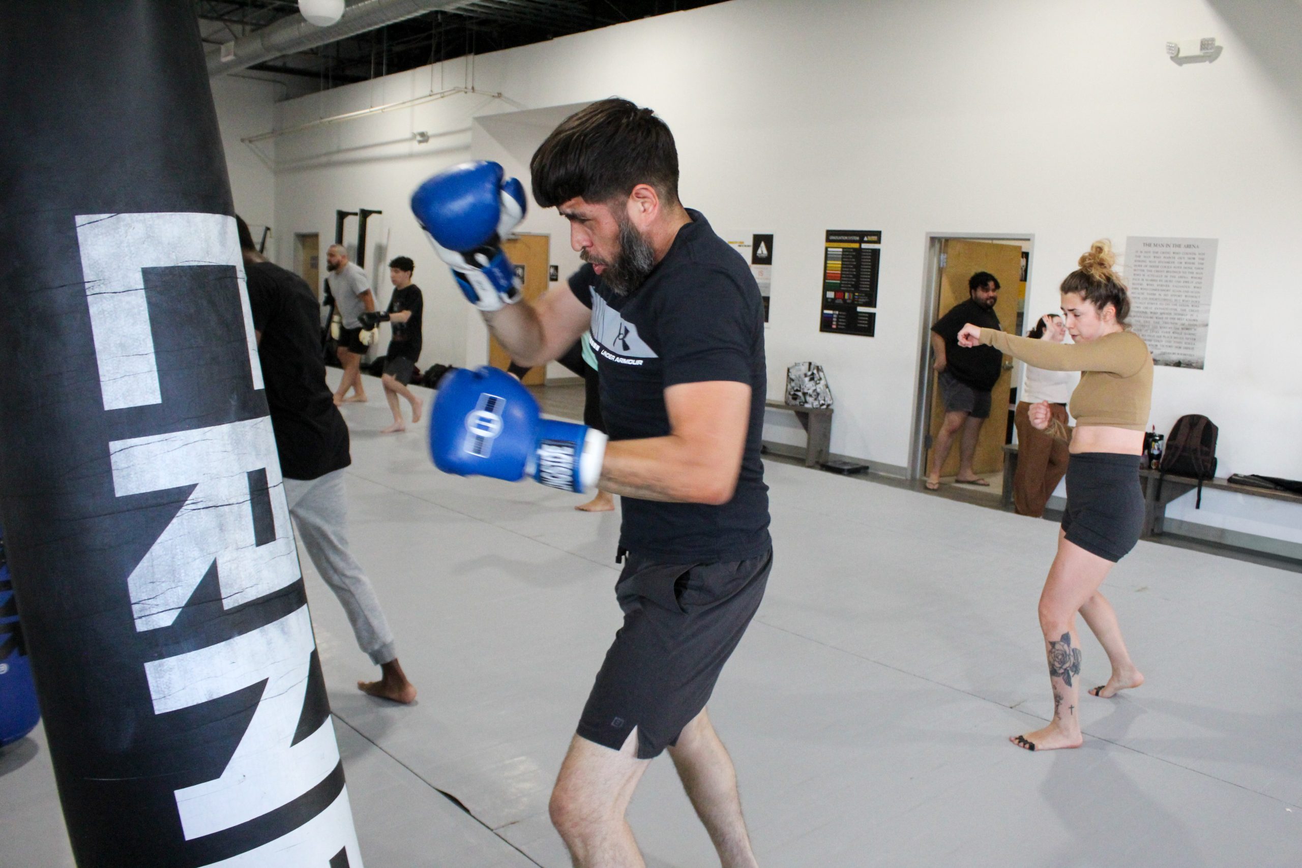 Adult striker working combinations on a heavy bag during a Muay Thai class