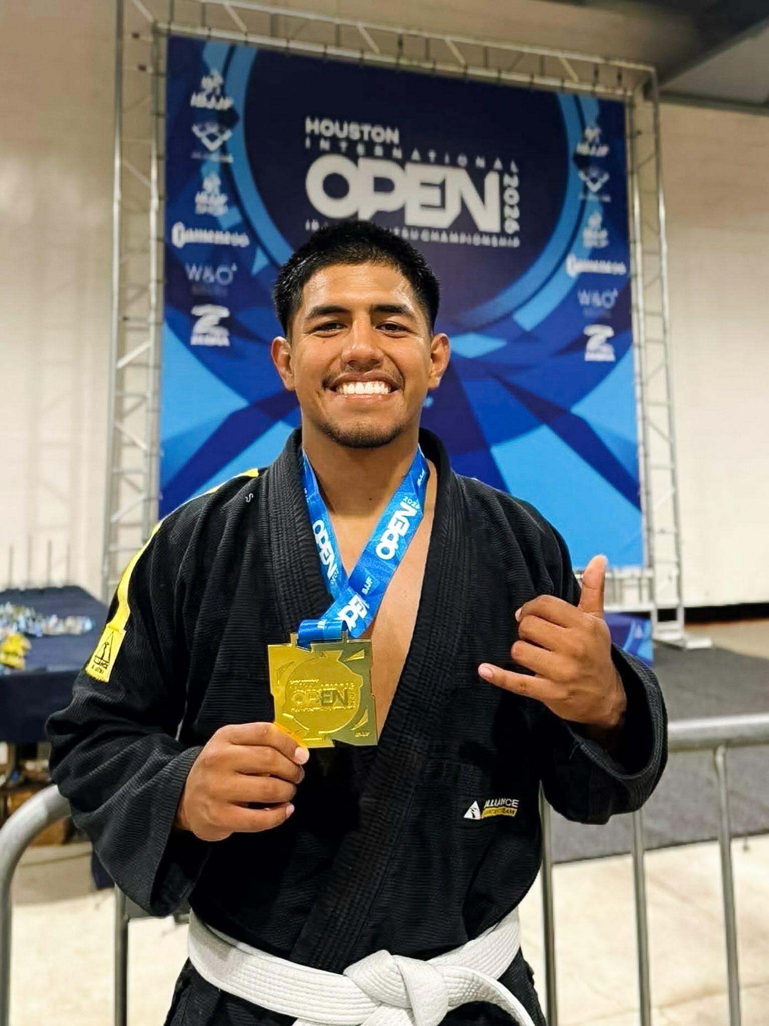 Alliance adult white belt holding a gold medal at IBJJF Houston International Open 2026