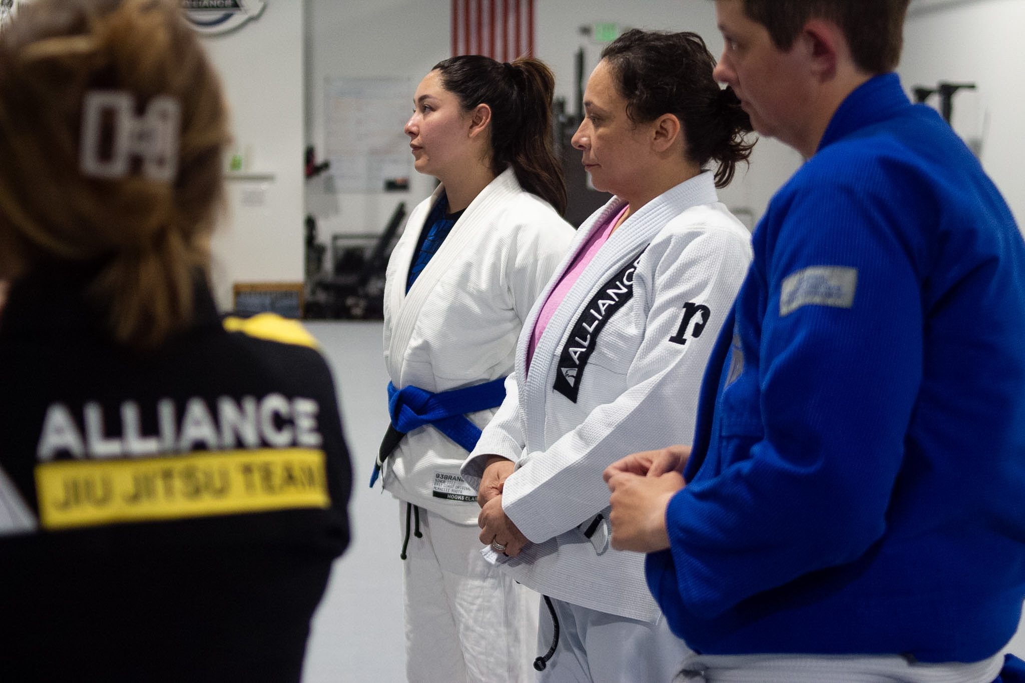 Women in Alliance gis gathered at the front of the mat during BJJ instruction