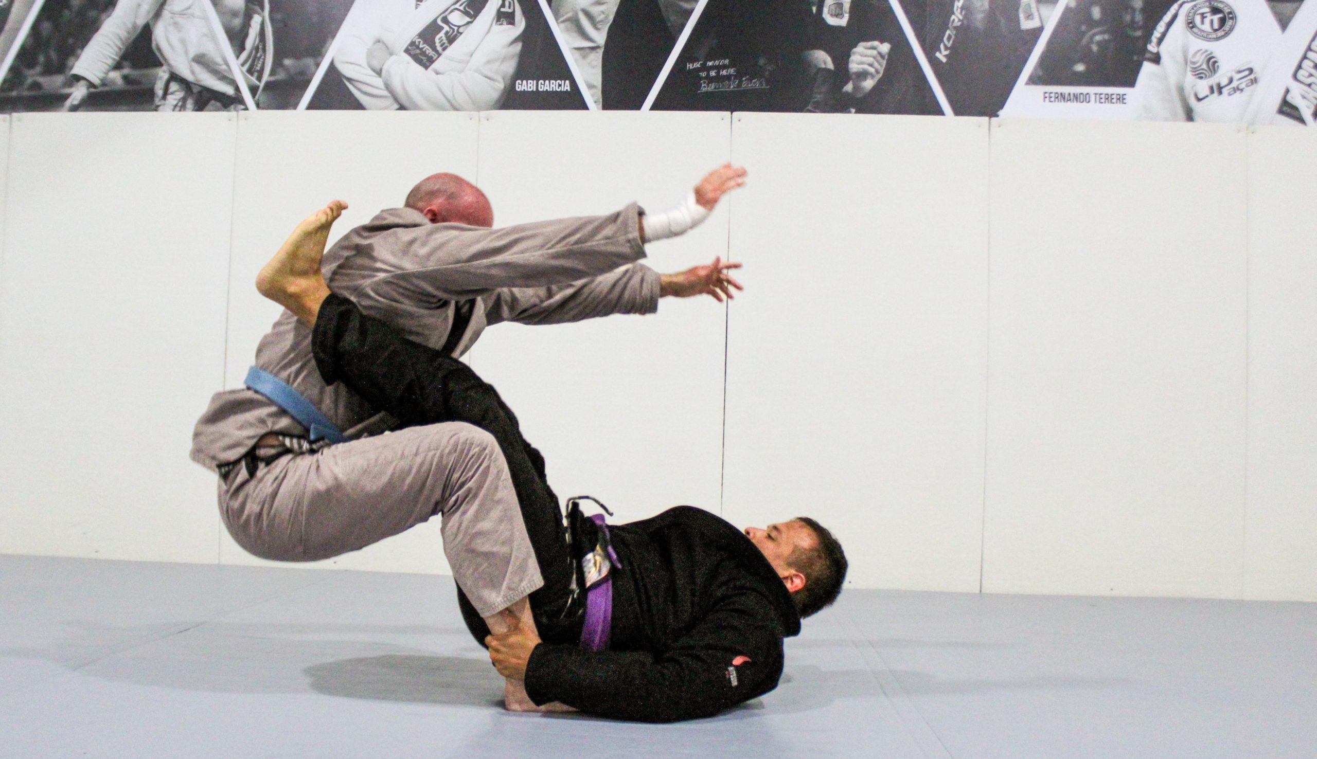 Purple belt sweeping a training partner from guard during adult BJJ class