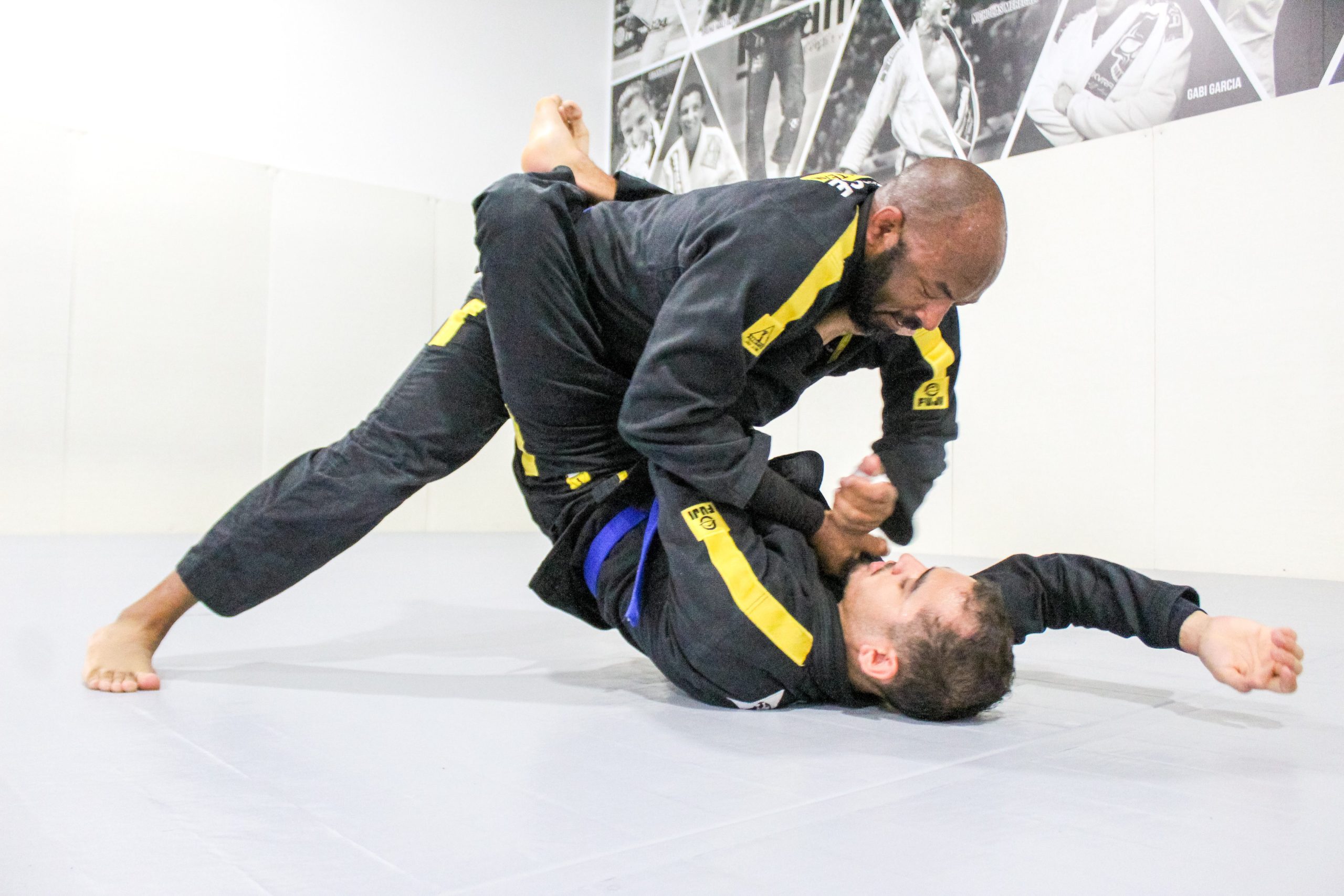 Black belt coach maintaining side control on a blue belt student during live drilling