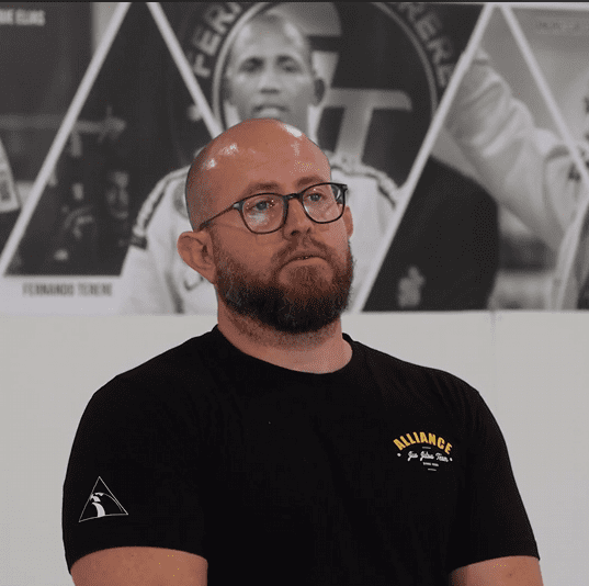 Clay Jasper sitting in front of the academy founders wall before his testimonial