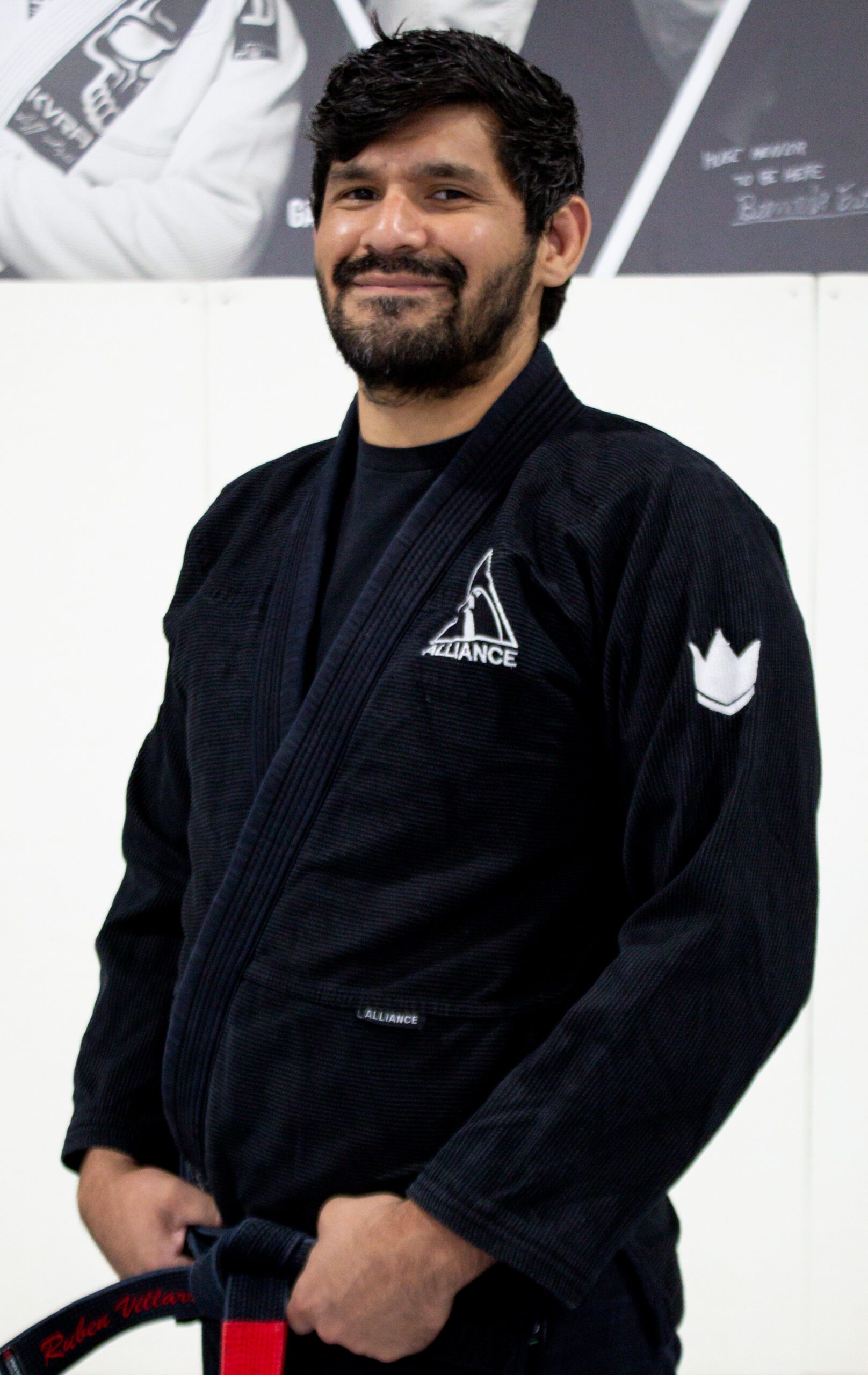 Coach Ruben in a black Alliance gi smiling at our Pearland academy