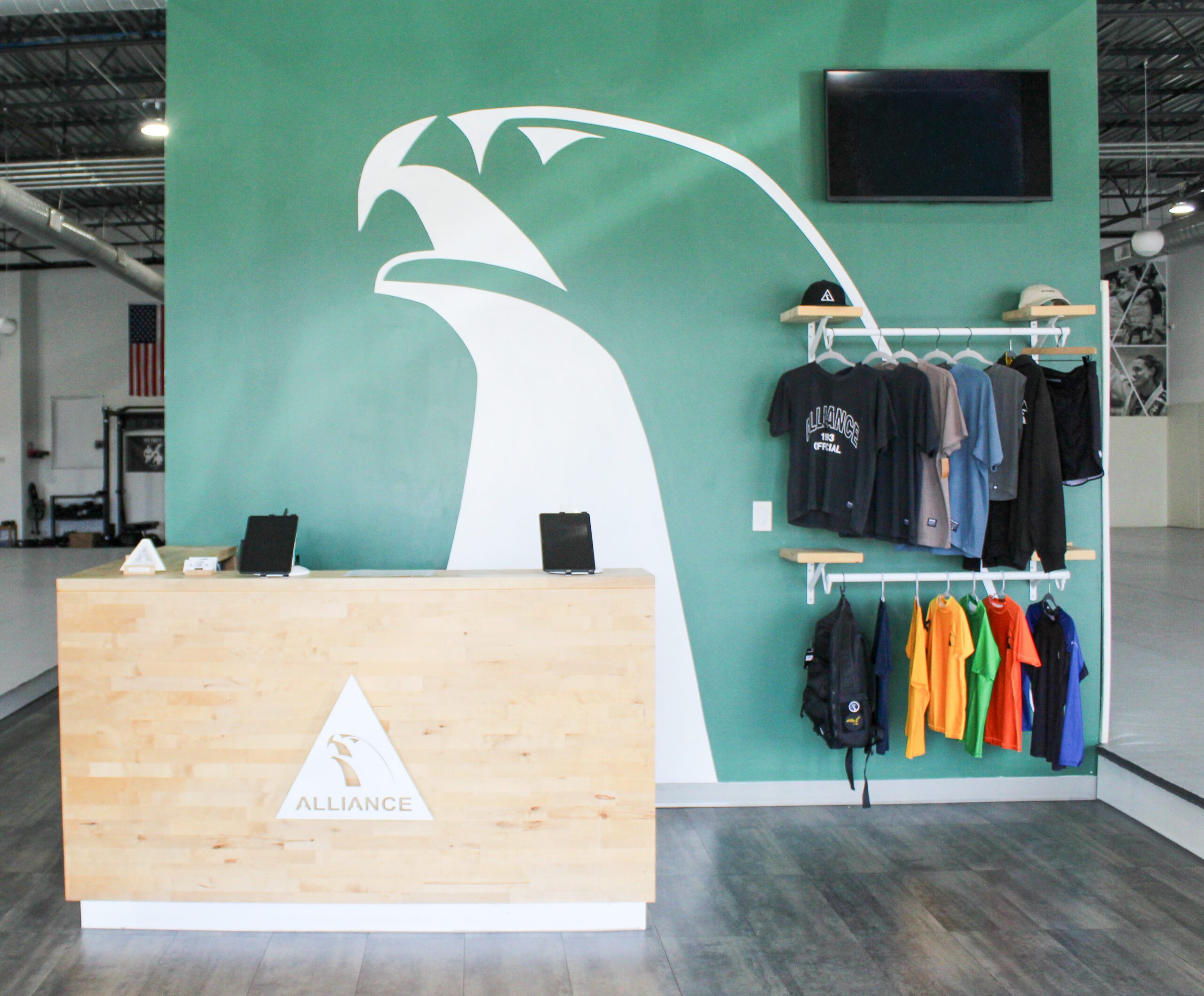 Wood front desk with the Alliance triangle logo and white eagle mural