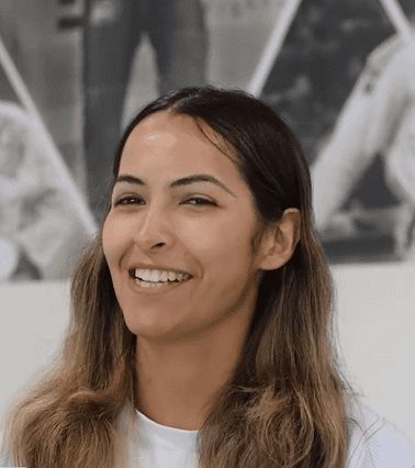 Gissel Cortez smiling in front of the academy photo wall during her testimonial