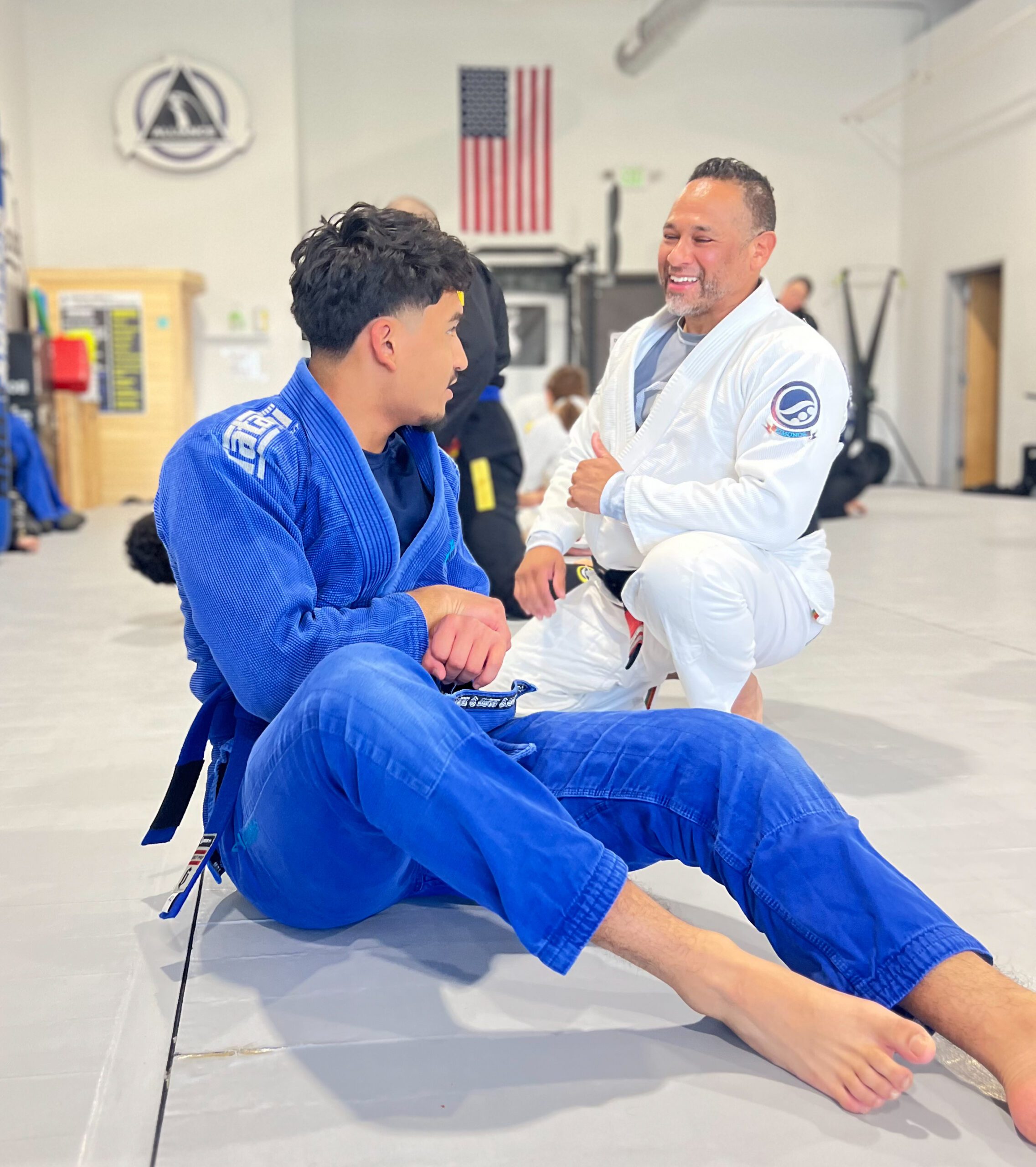 Alliance head coach laughing with a young blue belt mat-side at our Pearland academy