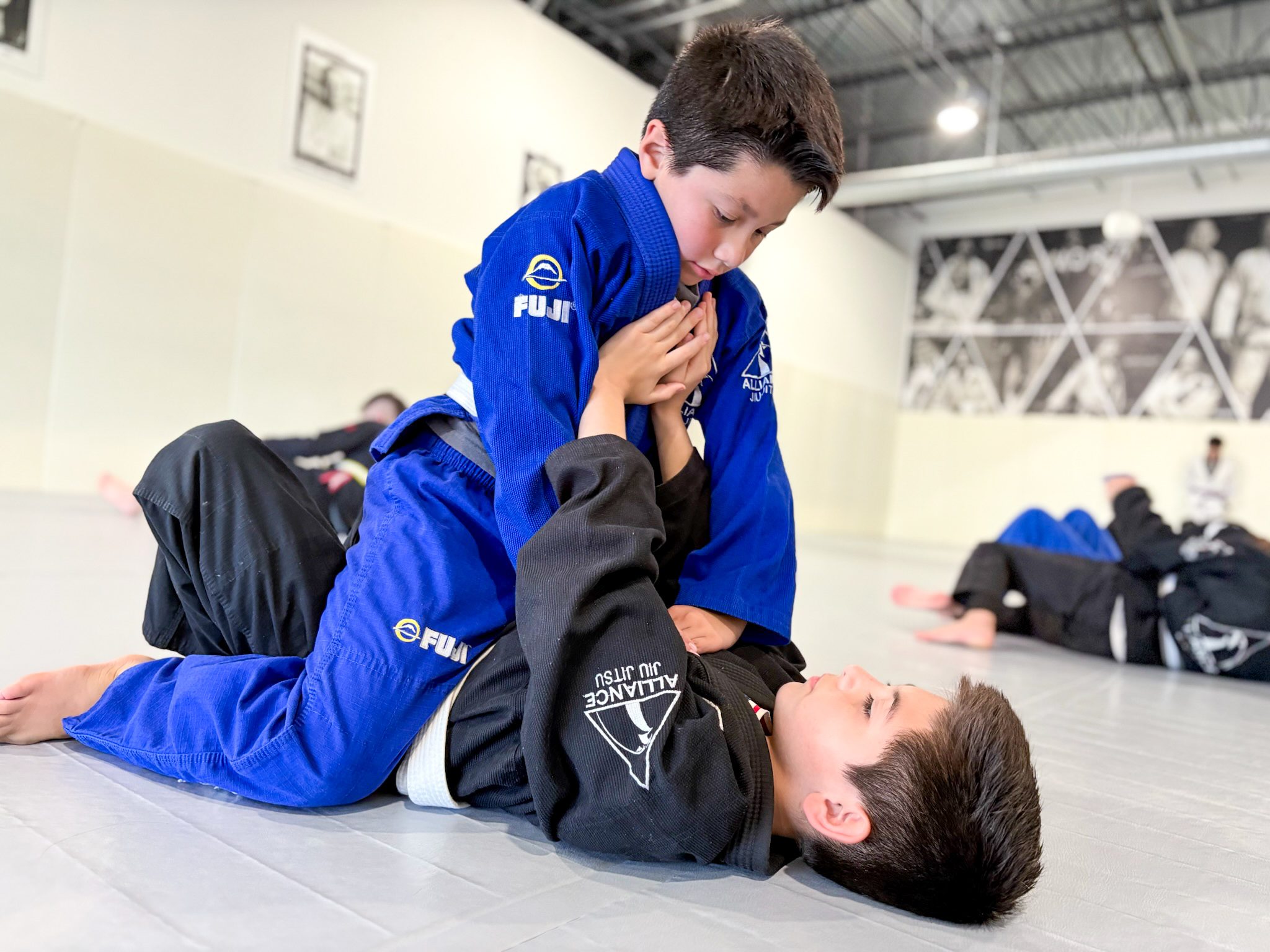 Two Junior Eagles students rolling on the mat in blue and black Alliance gis