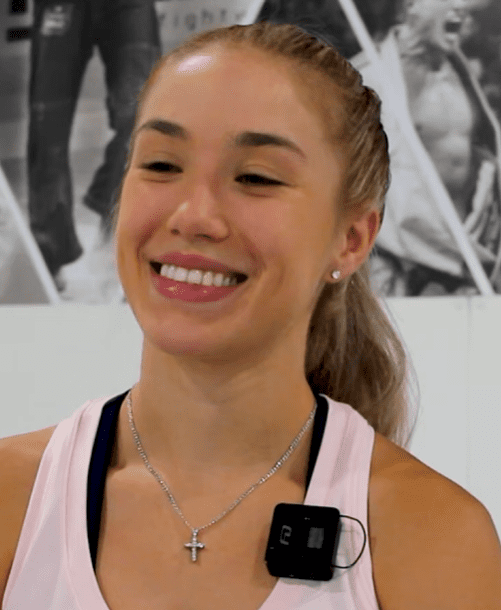 Marie Bailey smiling in athletic gear with a recording mic during her video testimonial