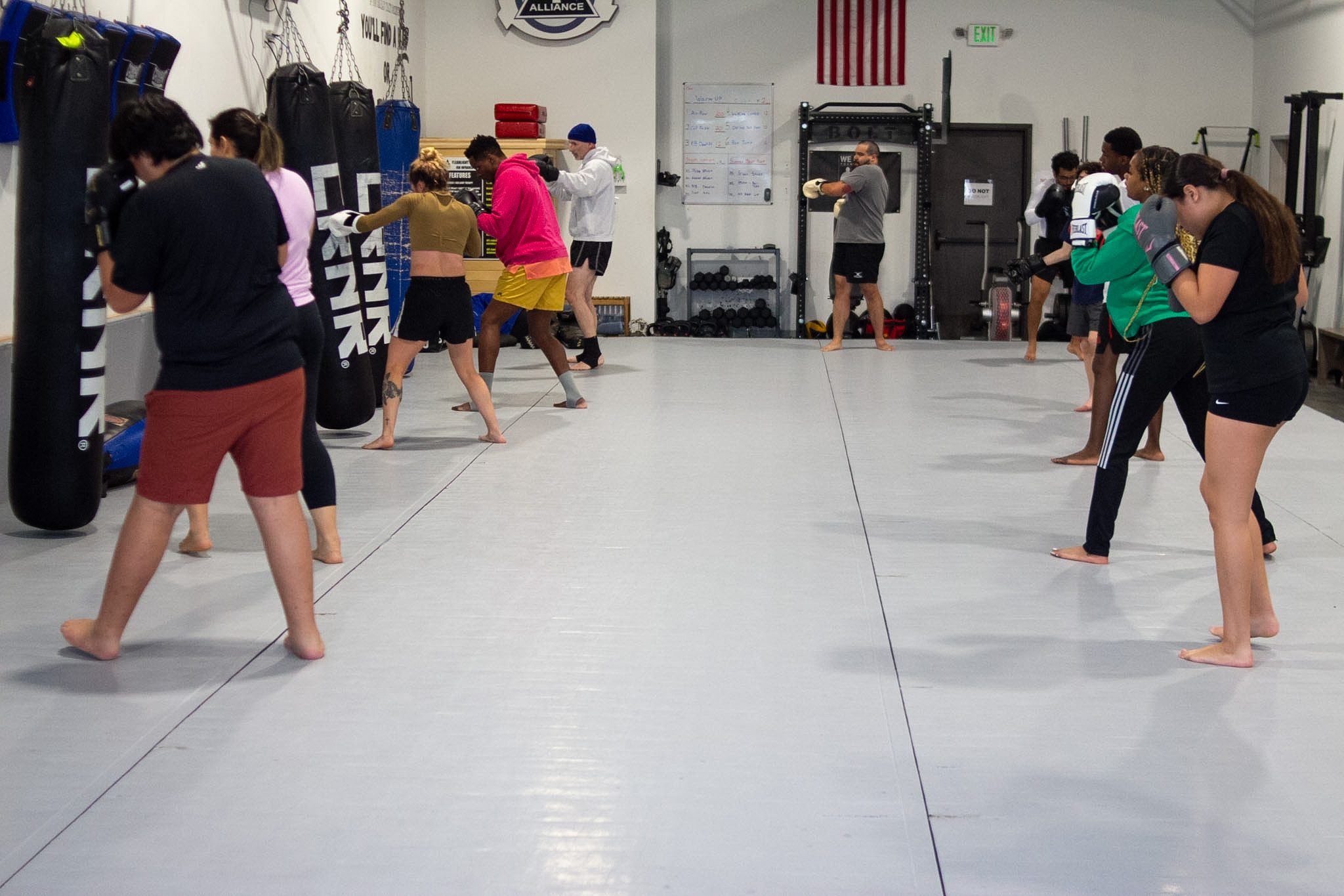 Wide view of a Muay Thai class lined up across the mat in fight stance