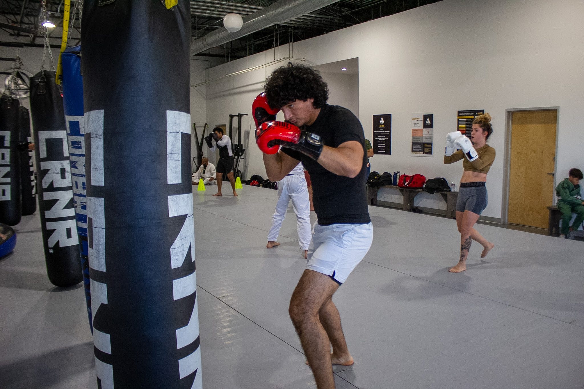Muay Thai student working focus mitts next to a heavy bag during class