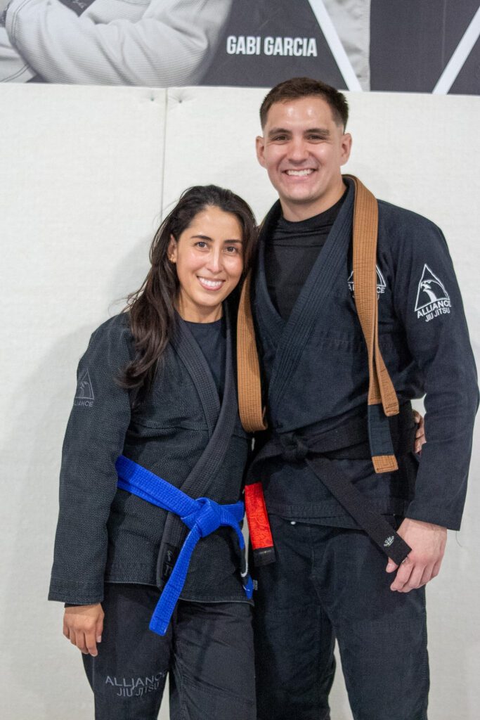 Thomas Dougherty in a black gi with a brown belt posing with a blue belt teammate