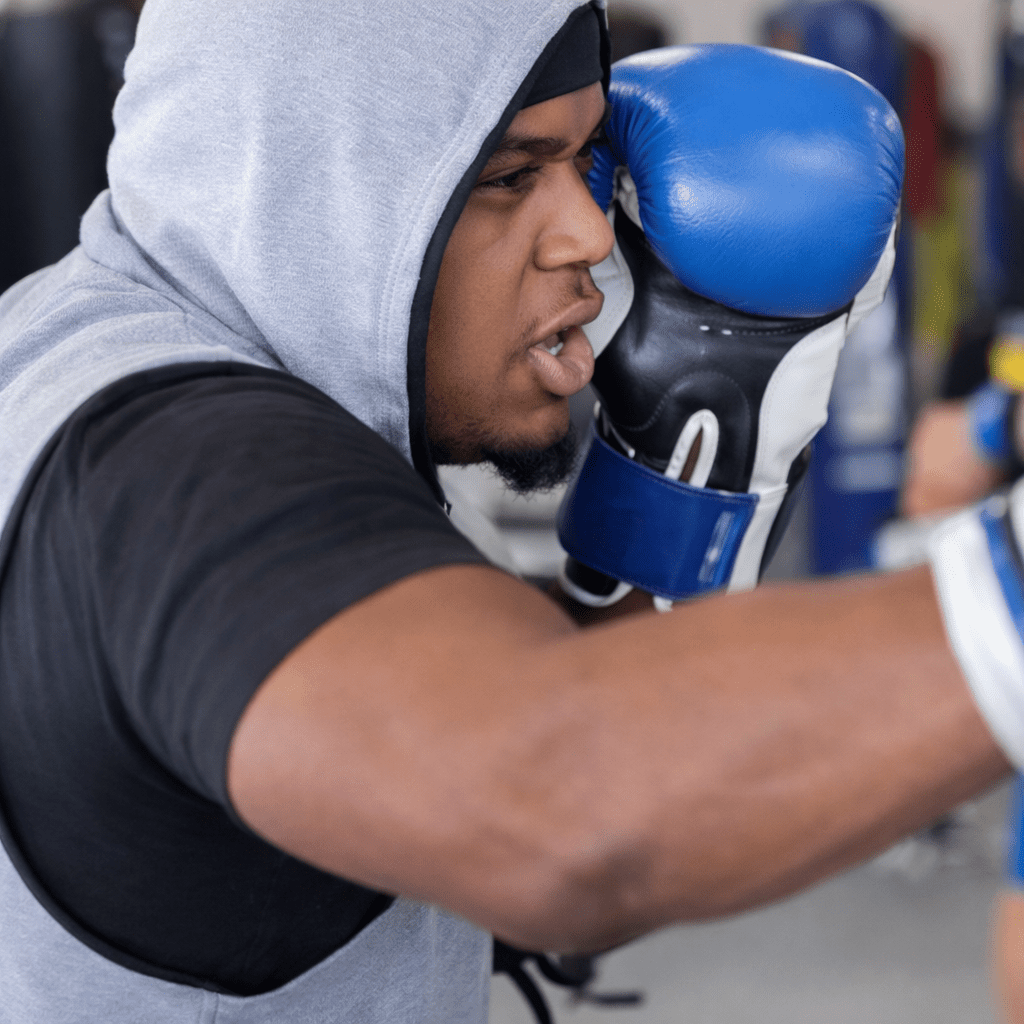 Voch Lombardi mid-strike in boxing gloves and a hoodie at our Pearland gym