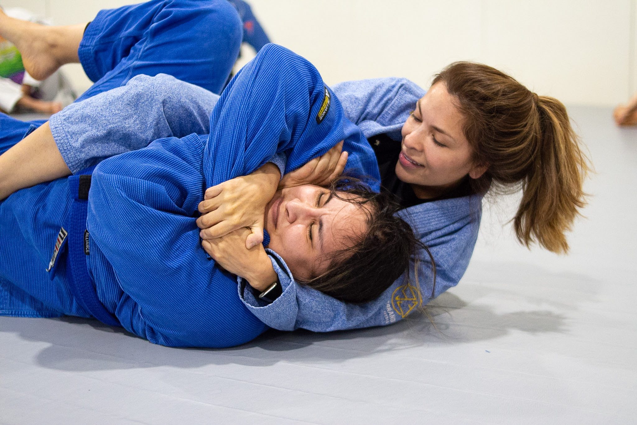 Two women training back control during Brazilian jiu-jitsu class