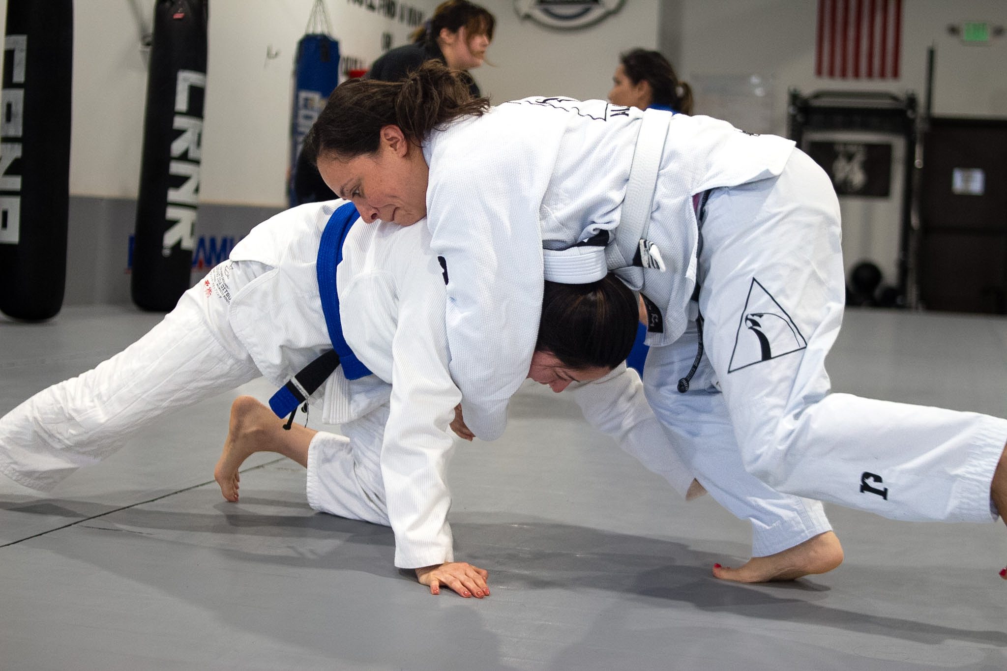 Two women grappling in top pressure position during jiu-jitsu class
