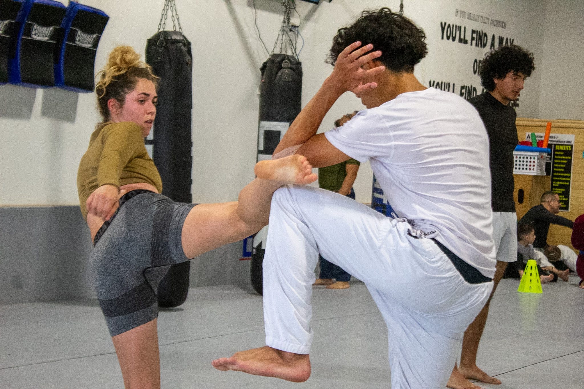 Young woman throwing a teep kick to a partner's midsection during Muay Thai class