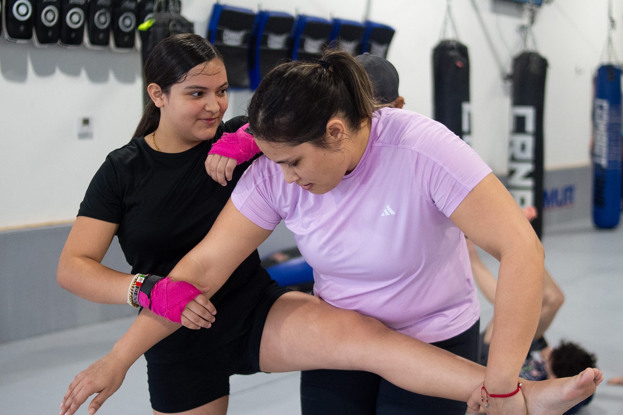 Two women working a knee strike drill together during Muay Thai class