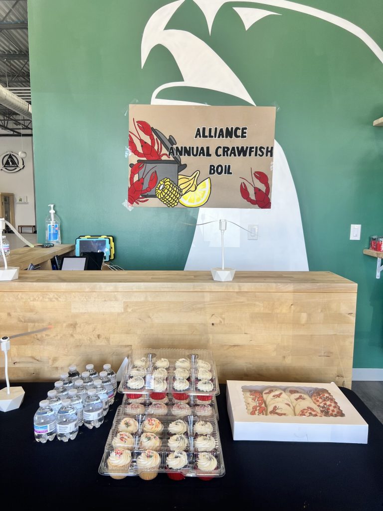 Hand-painted Alliance Annual Crawfish Boil banner above the front desk with cupcakes