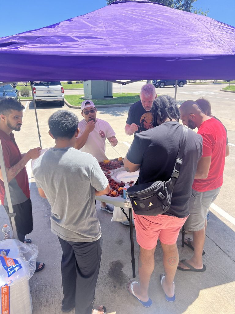 Group of Alliance jiu-jitsu members gathered around the boil table under purple canopy