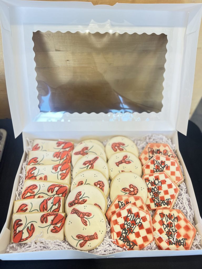 Hand-decorated crawfish sugar cookies and pinch peel repeat cookies in white bakery box