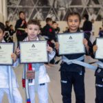 Four young Alliance students hold framed belt certificates after promotion ceremony