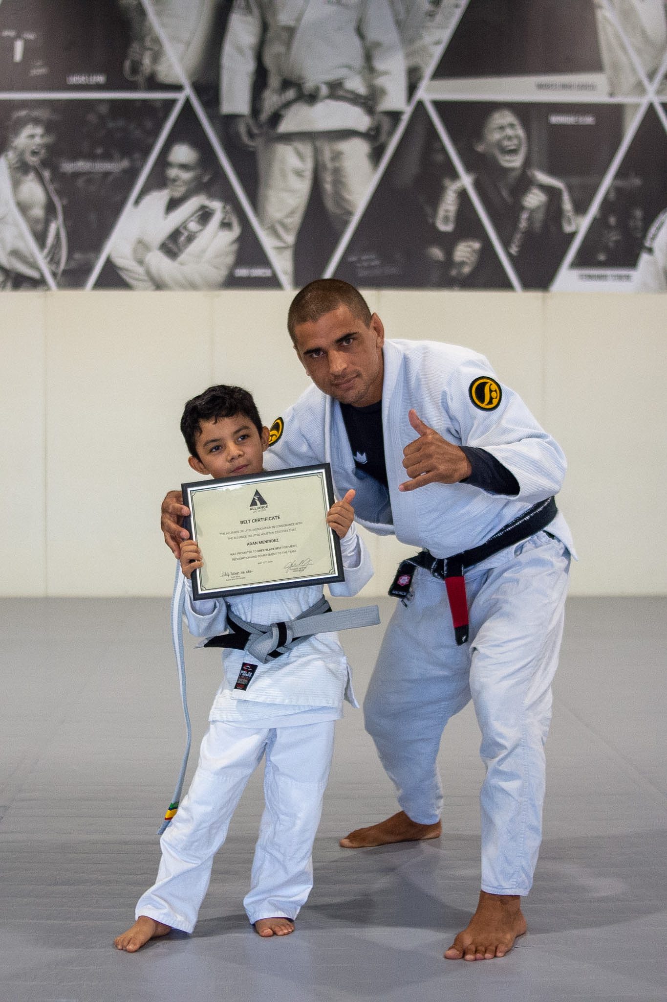Smiling young student shows off framed Alliance belt promotion certificate