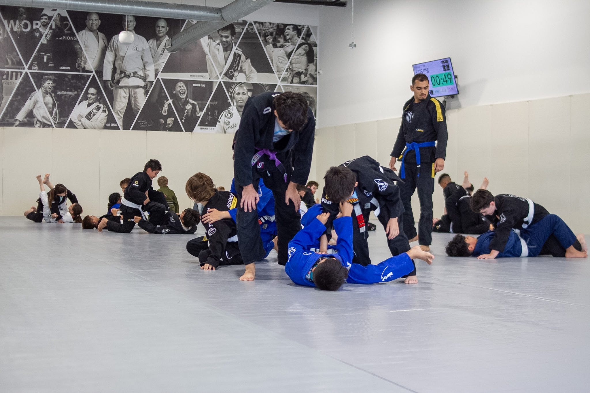 Wide view of Alliance kids jiu-jitsu class drilling positions across the mat
