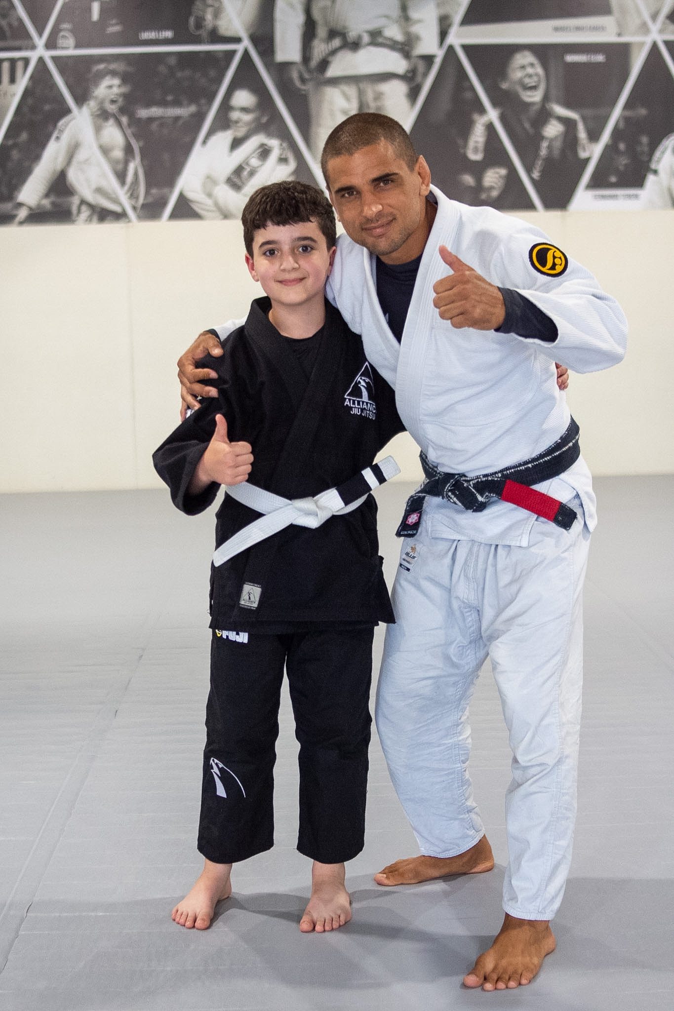Little Eagle in black gi stands beside head instructor for promotion photo