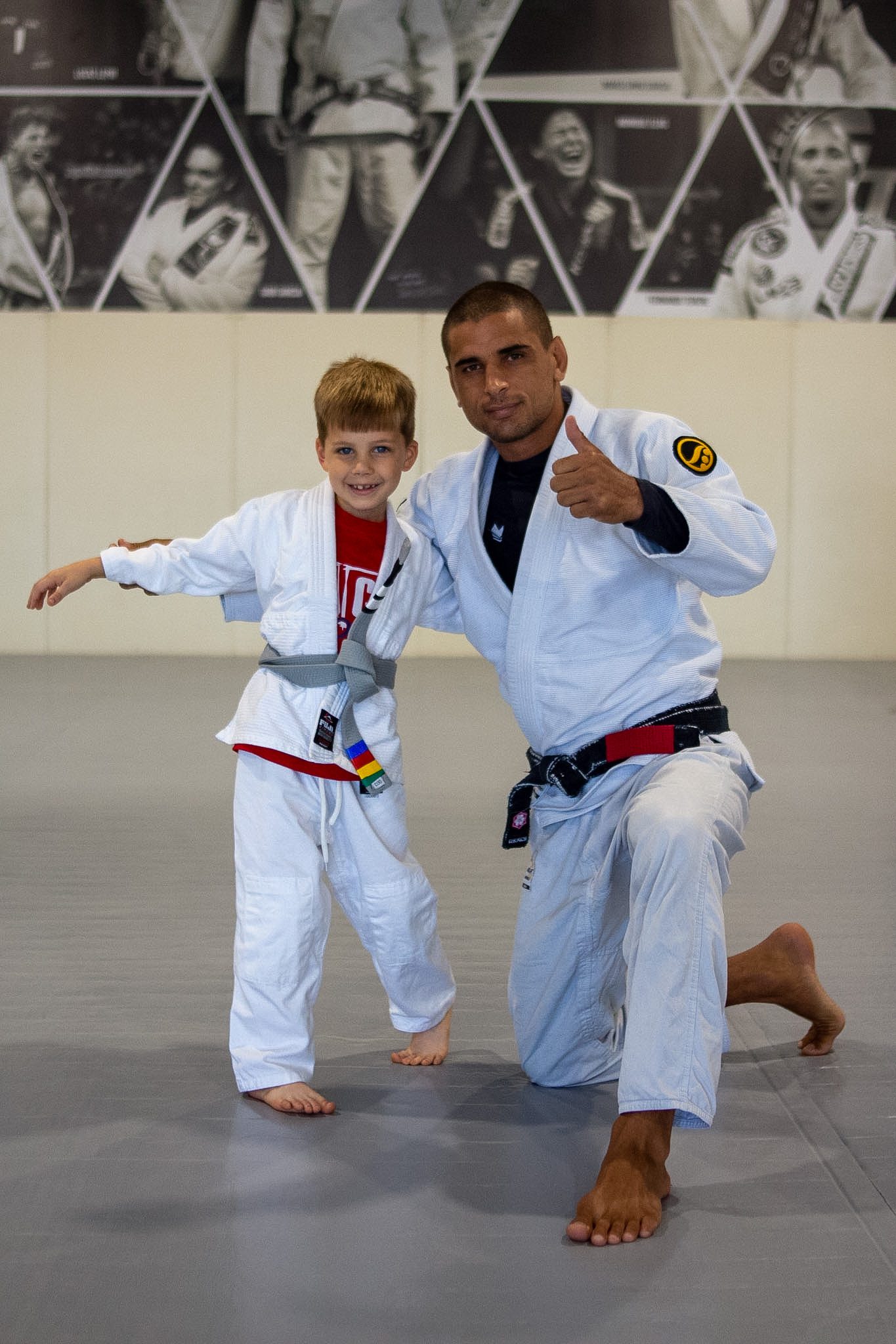 Excited Tiny Eagle in white gi raises his hand with new grey-white belt
