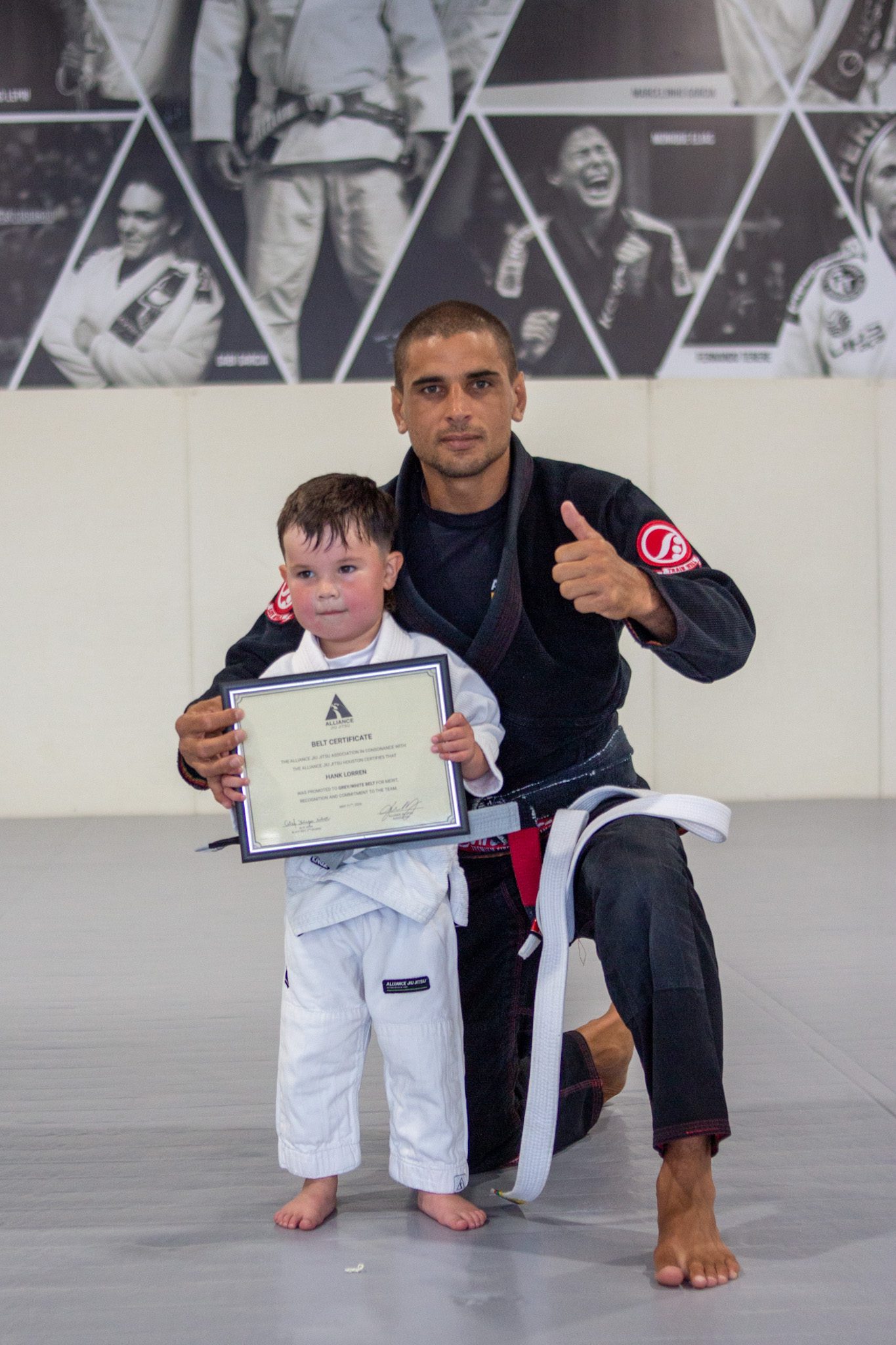 Small Tiny Eagle in black gi holds belt certificate beside head black belt instructor
