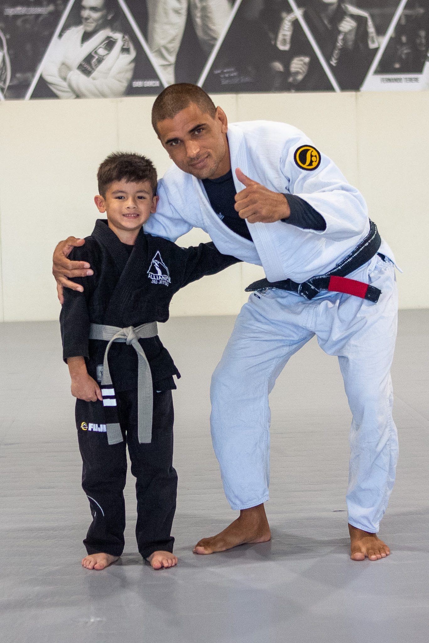 Head instructor Alef Silva poses with smiling Tiny Eagle in new grey-white belt