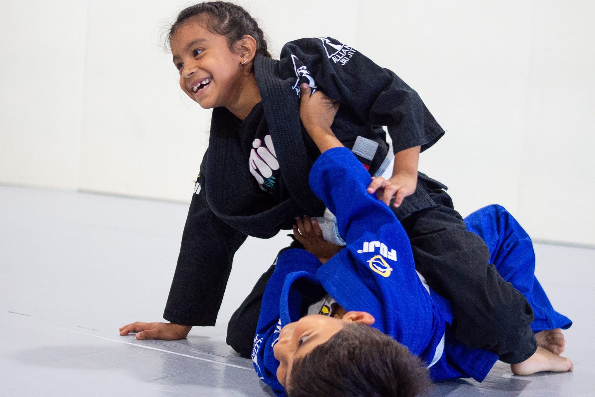 Young girl smiles while holding mount during a kids jiu-jitsu round
