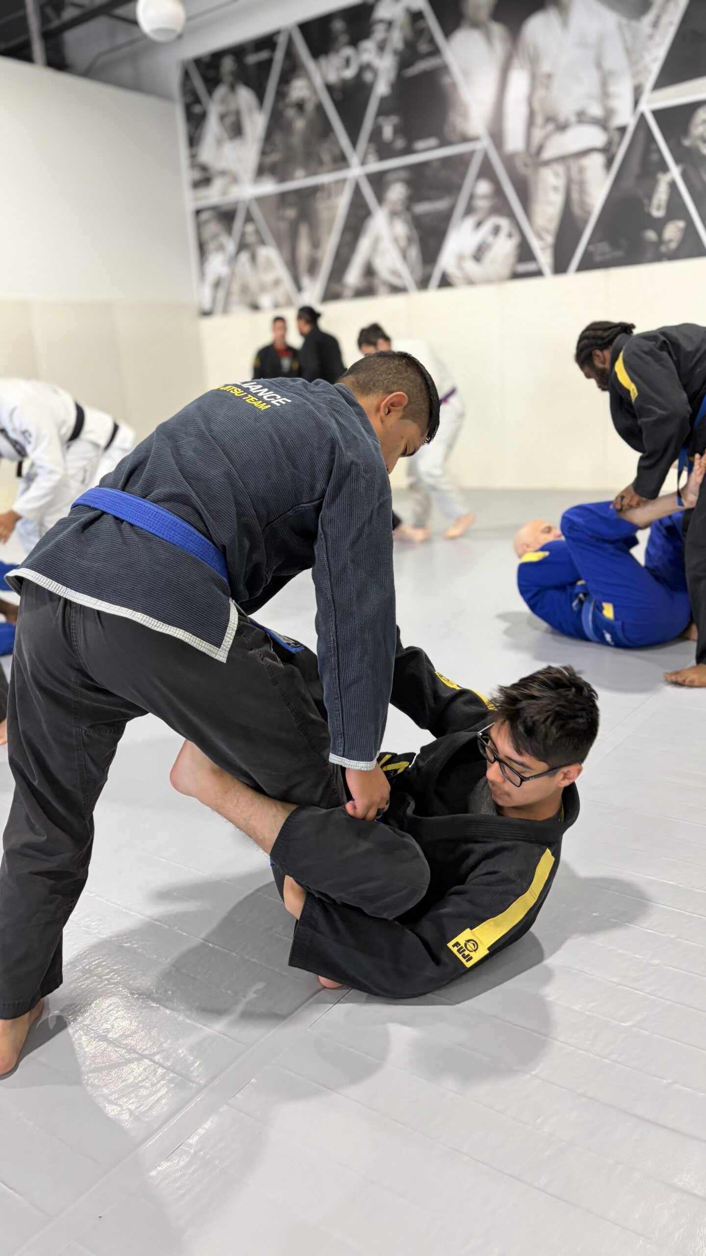 Grappler in a black gi controls a partner during a live round