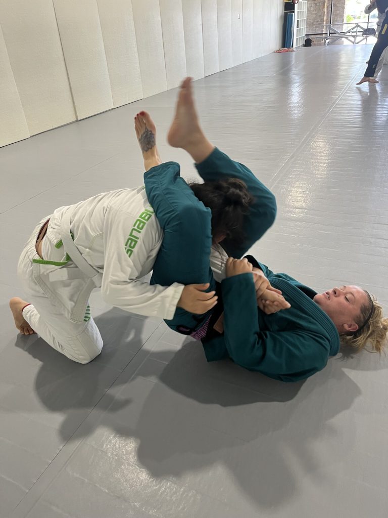Woman controls her training partner from guard during a women's jiu-jitsu self-defense class