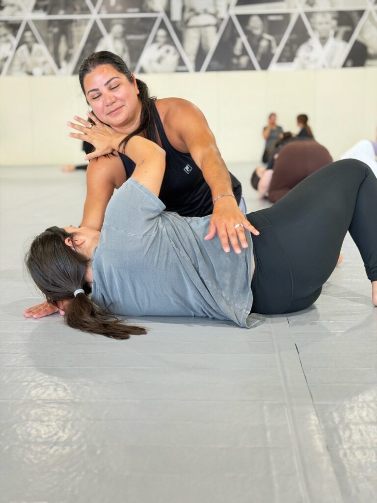 Bottom student bridges and turns to her side while escaping during a grappling drill