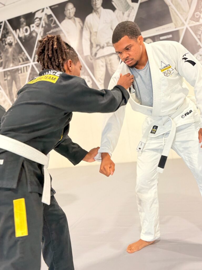 White belt in black Alliance gi sets up a takedown entry