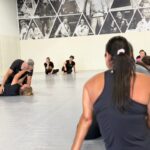 Students watch an Alliance instructor demonstrate a self-defense escape from the mat
