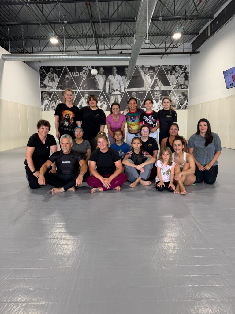 Women and girls gather with their instructor after a Pearland jiu-jitsu seminar