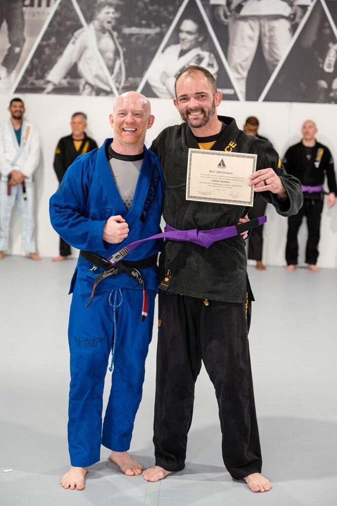 Jeremy Woodin holds his purple belt certificate beside Professor Danny Duckworth
