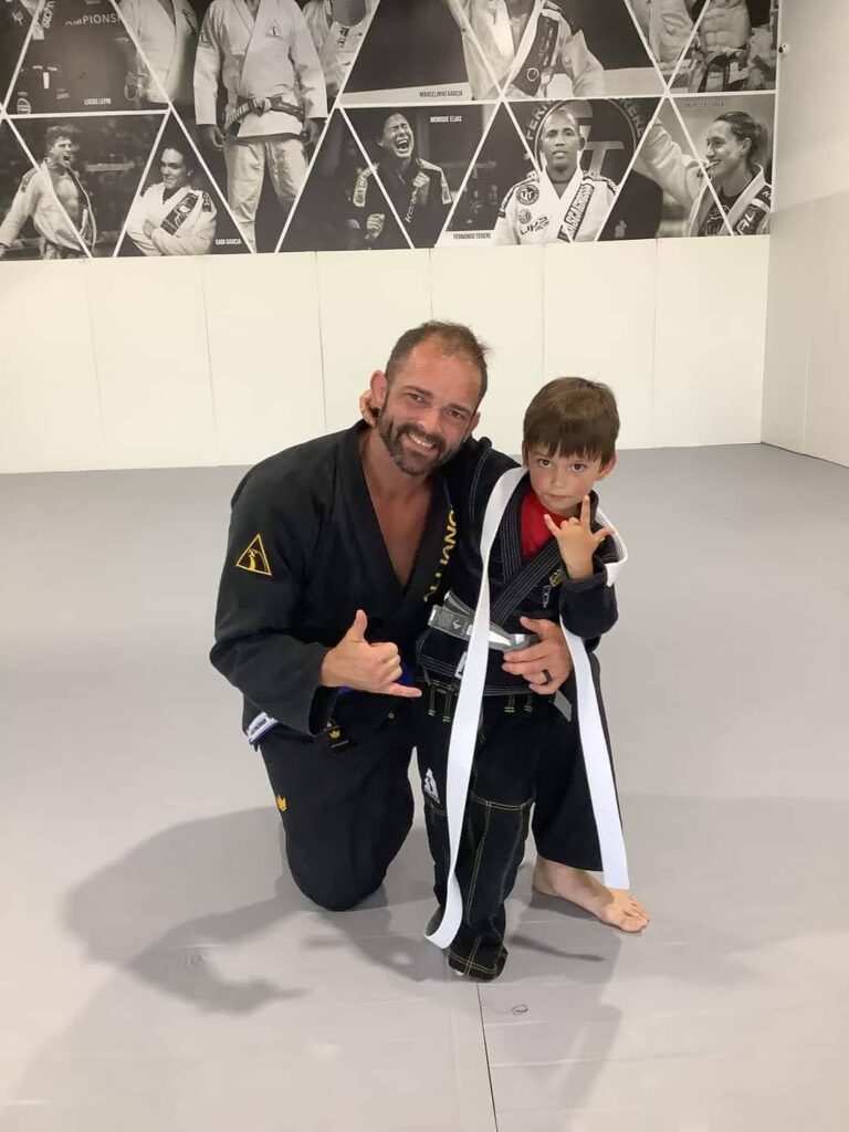 Jeremy Woodin kneels beside his young son, who wears a new kids belt